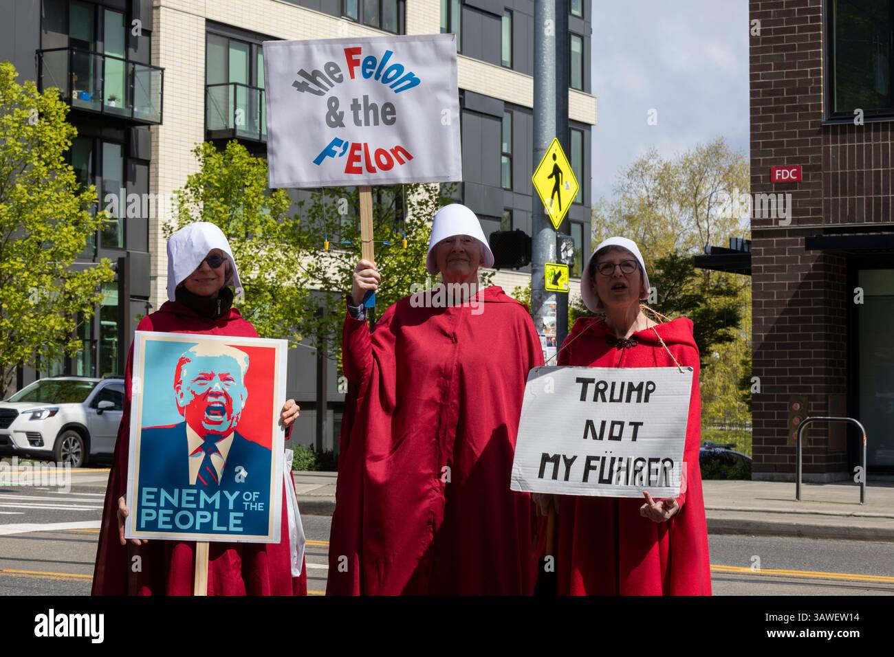 Seattle, Washington, USA. 19th April 2025. Protesters costumed as characters from 'The Handmaid's Tale' pose for a photo along Broadway Ave during the 'We the People Means Everyone' rally and march in Seattle on Saturday, April 19, 2025. The demonstration in support of democracy, diversity and equity is part of a national day of action against actions of the Trump administration. Credit: Paul Christian Gordon/Alamy Live News Stock Photo