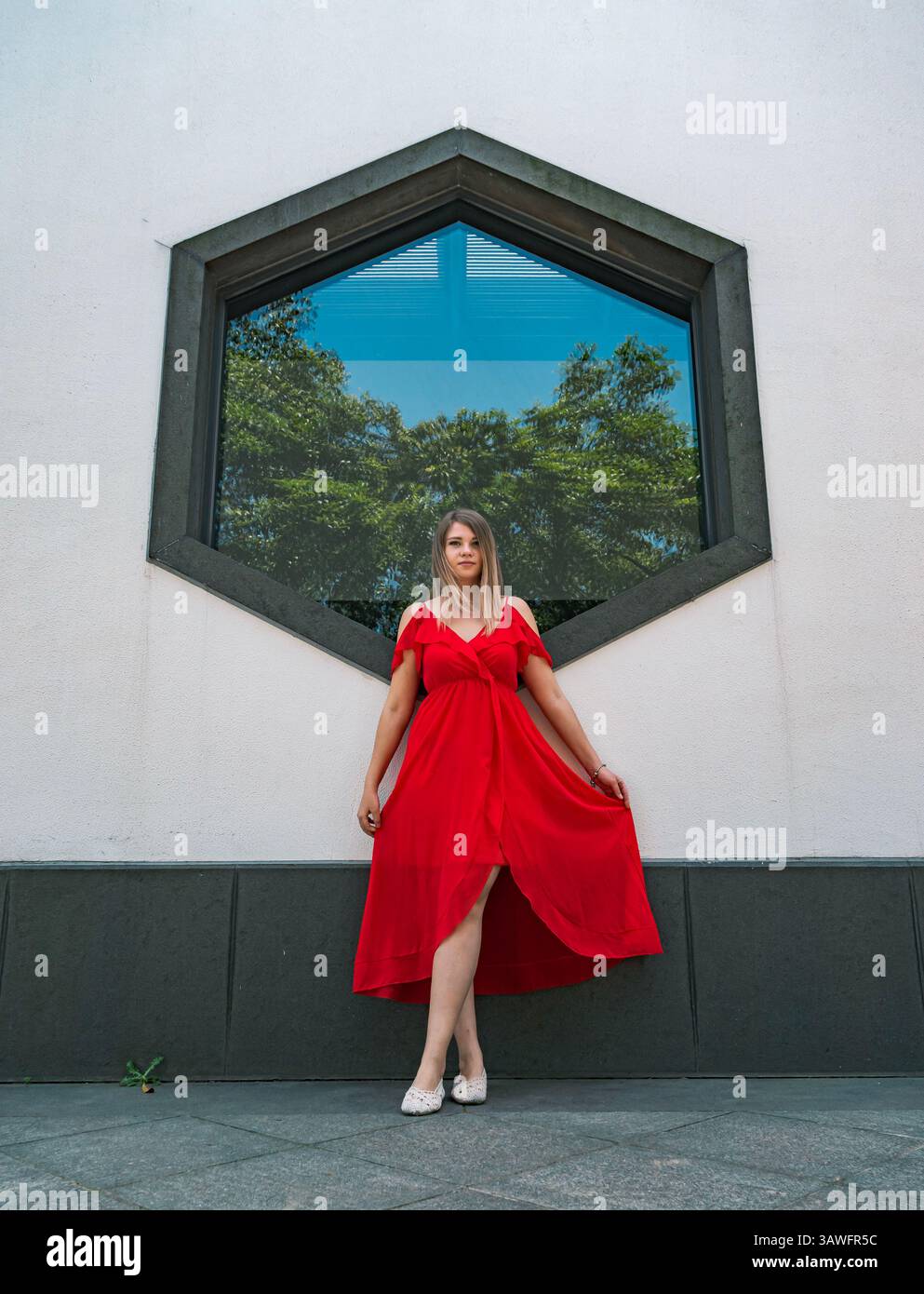 A woman stands elegantly in a flowing red dress, striking a pose in ...