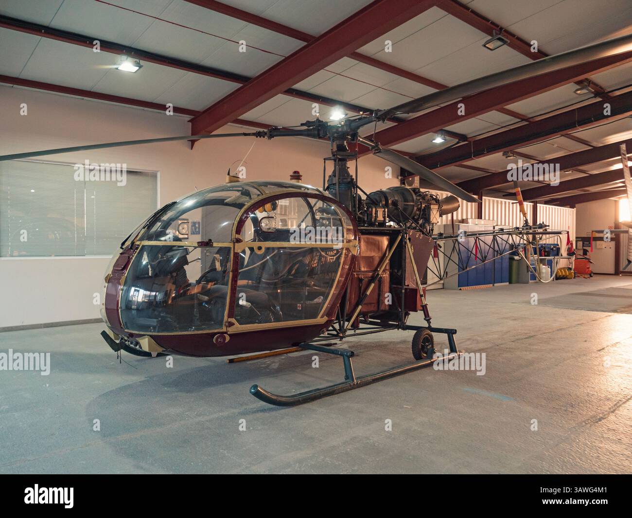 Vintage helicopter parked indoors in a well-lit hangar Stock Photo