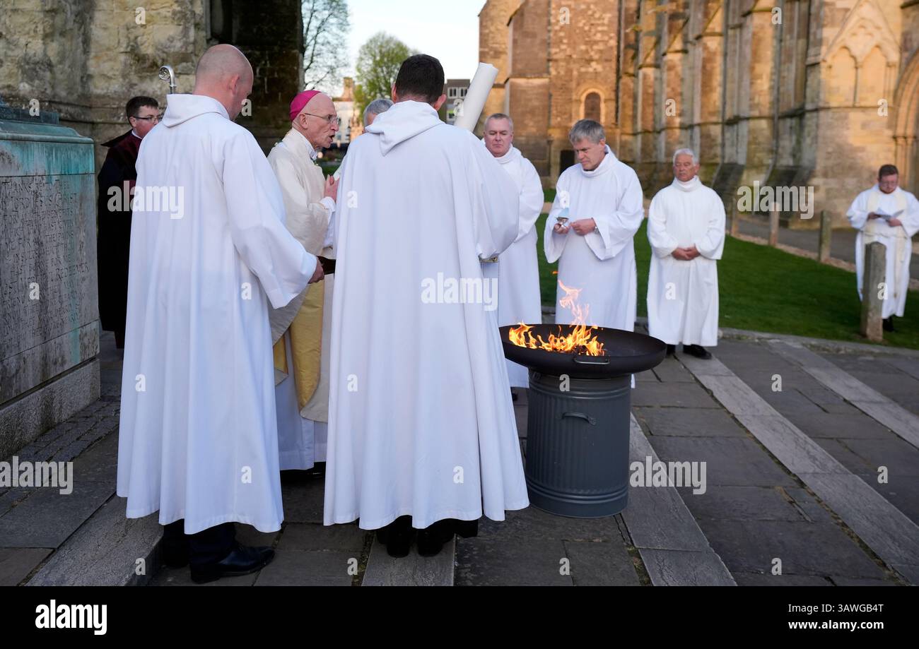 The Bishop of Chichester, The Right Reverend Dr Martin Warner (2nd left) blesses the fire before the lighting the Paschal Candle outside of Chichester Cathedral ahead of the Easter Vigil. Picture date: Saturday April 19, 2025. Stock Photo