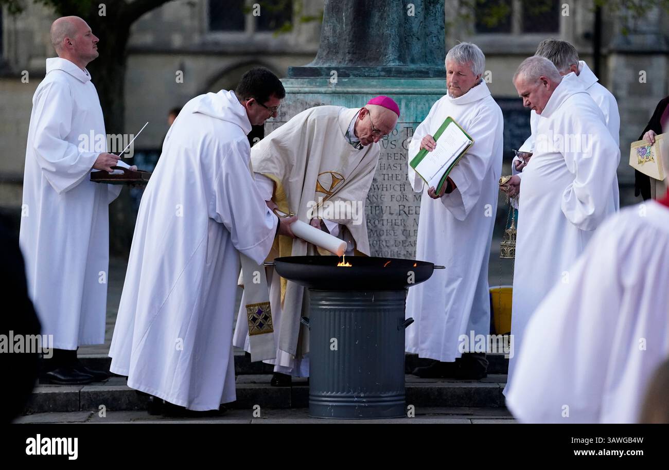 The Bishop of Chichester, The Right Reverend Dr Martin Warner (centre) lights the Paschal Candle outside of Chichester Cathedral ahead of the Easter Vigil. Picture date: Saturday April 19, 2025. Stock Photo