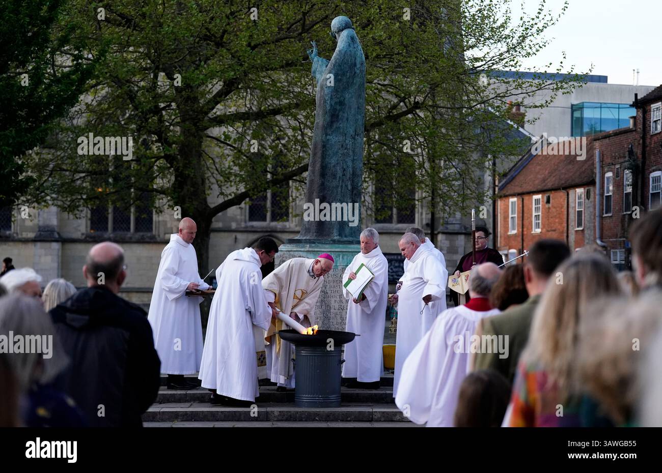The Bishop of Chichester, The Right Reverend Dr Martin Warner (centre) lights the Paschal Candle outside of Chichester Cathedral ahead of the Easter Vigil. Picture date: Saturday April 19, 2025. Stock Photo