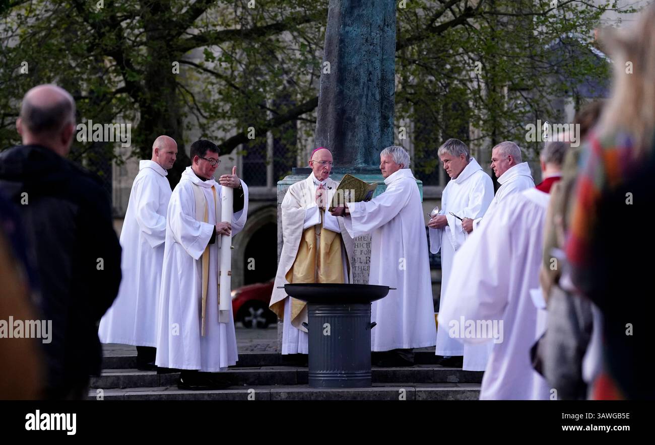 The Dean of Chichester Cathedral, The Very Reverend Dr. Edward Dowler holds the Paschal Candle as the Bishop of Chichester, The Right Reverend Dr Martin Warner gives a blessing outside of Chichester Cathedral, after the candle was lit in a ceremony ahead of the Easter Vigil. Picture date: Saturday April 19, 2025. Stock Photo