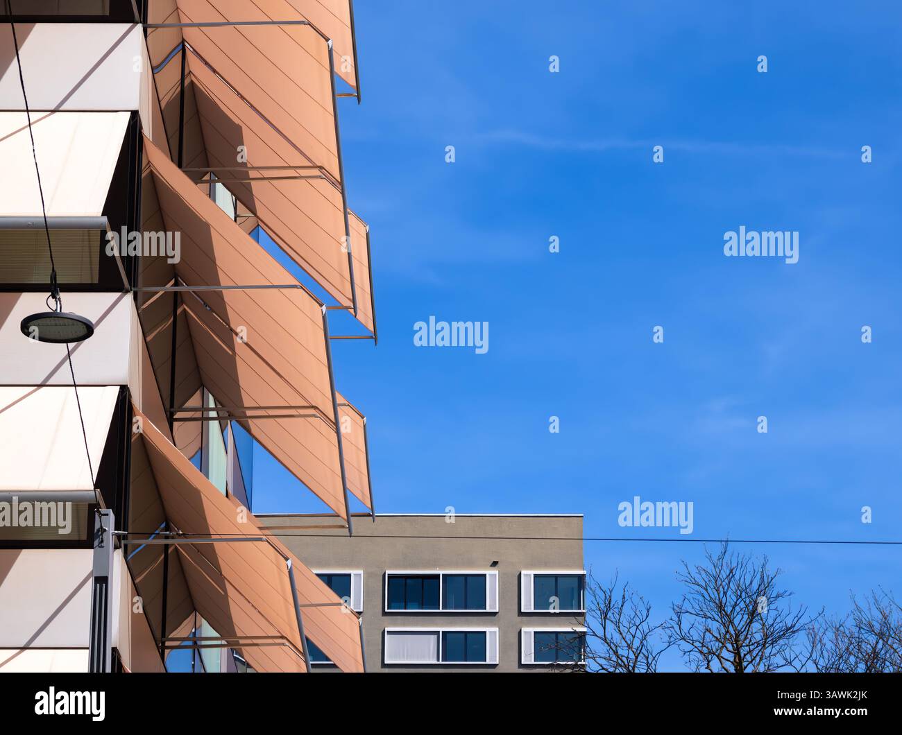 Modern architectural facade with angular panels against a clear blue ...