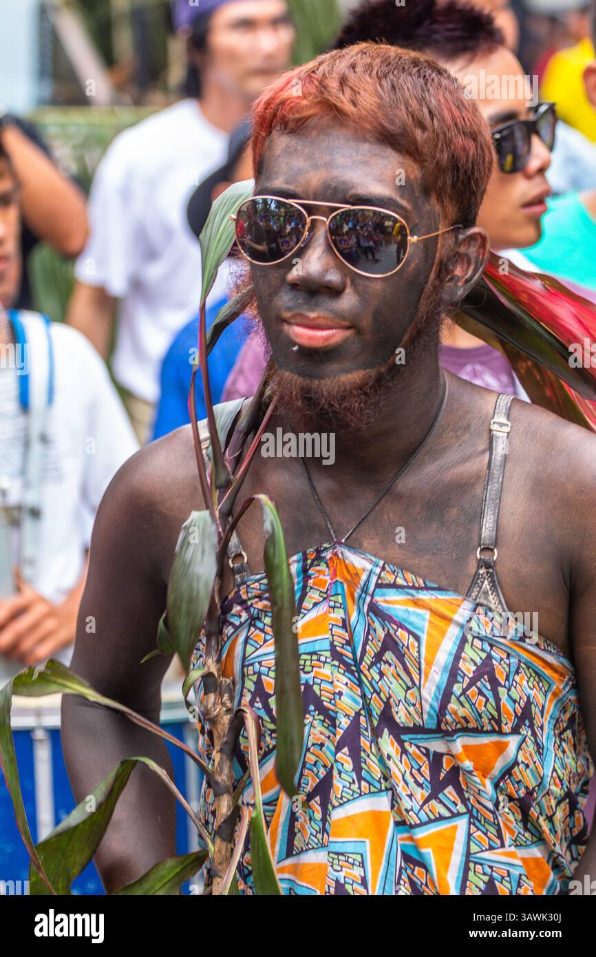 A man wearing a woman's clothing joins the Ati-Ati Festival in Aklan, Philippines in a festive mood celebrating tradition and local culture Stock Photo