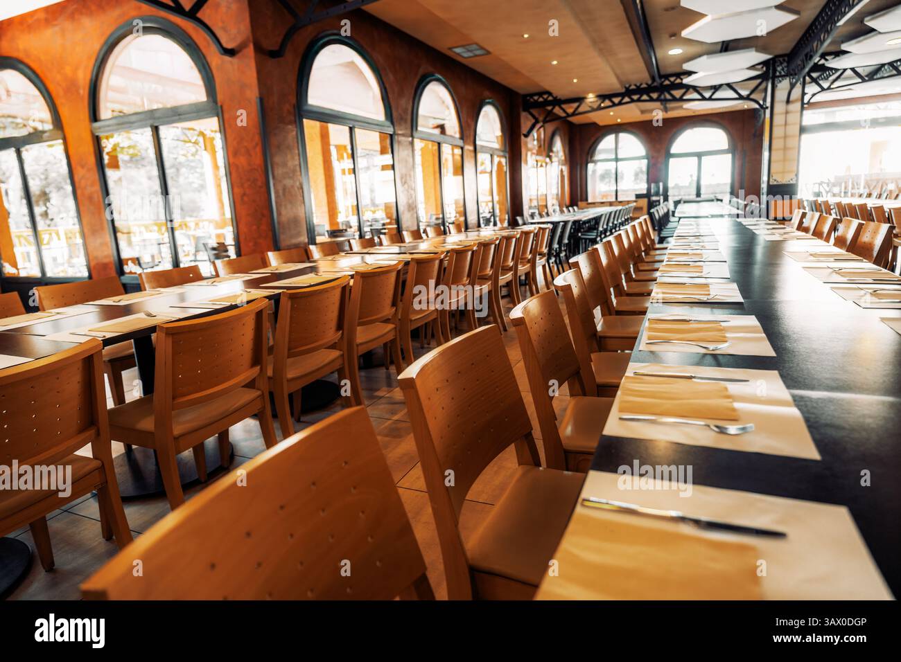 Spacious empty restaurant interior with long neatly set dining tables ...