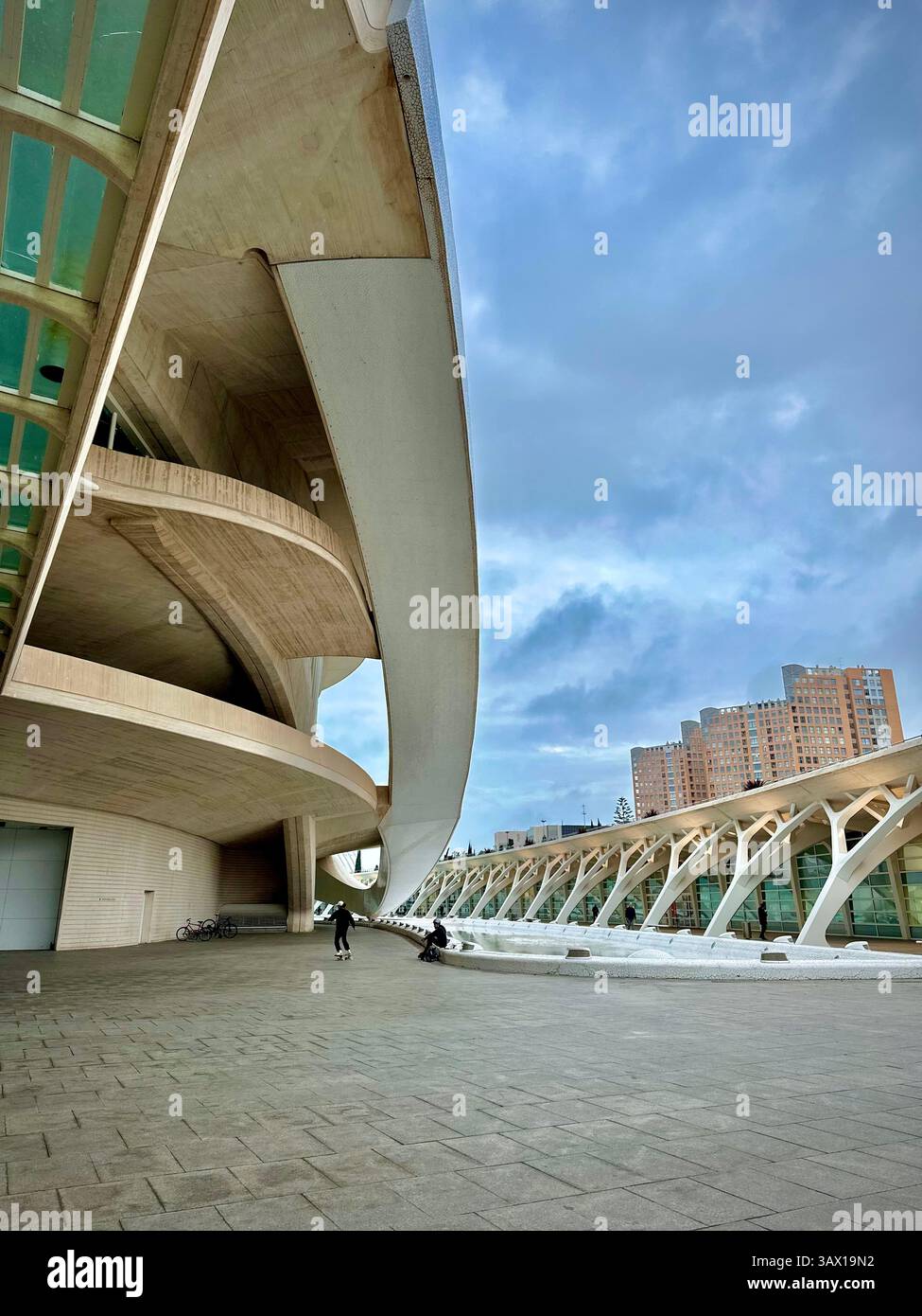 Skaters in action beneath a futuristic building in Valencia, combining urban life and modern design. - Smartphone Captured Stock Image