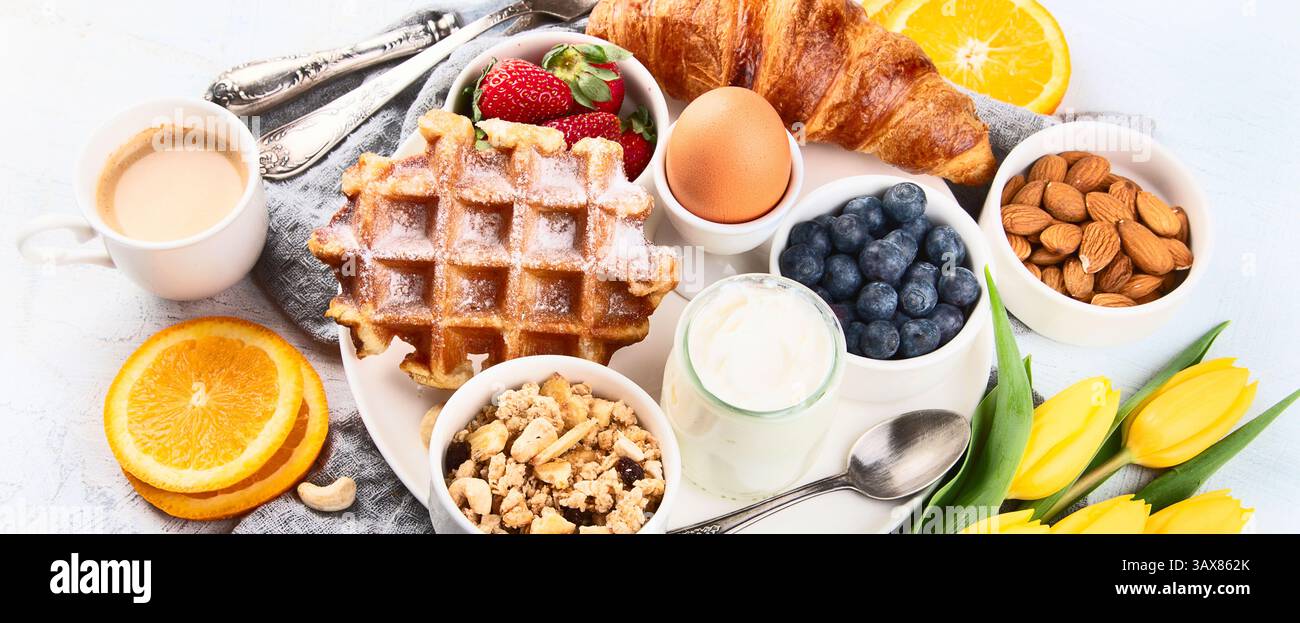 Breakfast table with eggs, berries, yogurt, waffle and croissant ...
