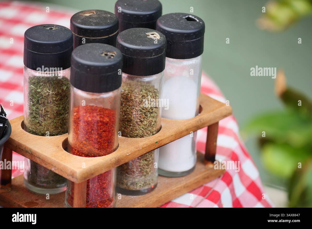 Spice jars on wooden rack at outdoor dining table setting Stock Photo