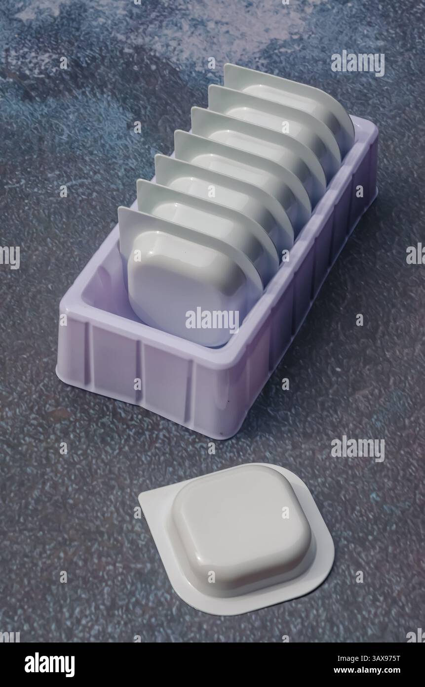 Stack of single-use plastic containers for sauce or detergent. High ...