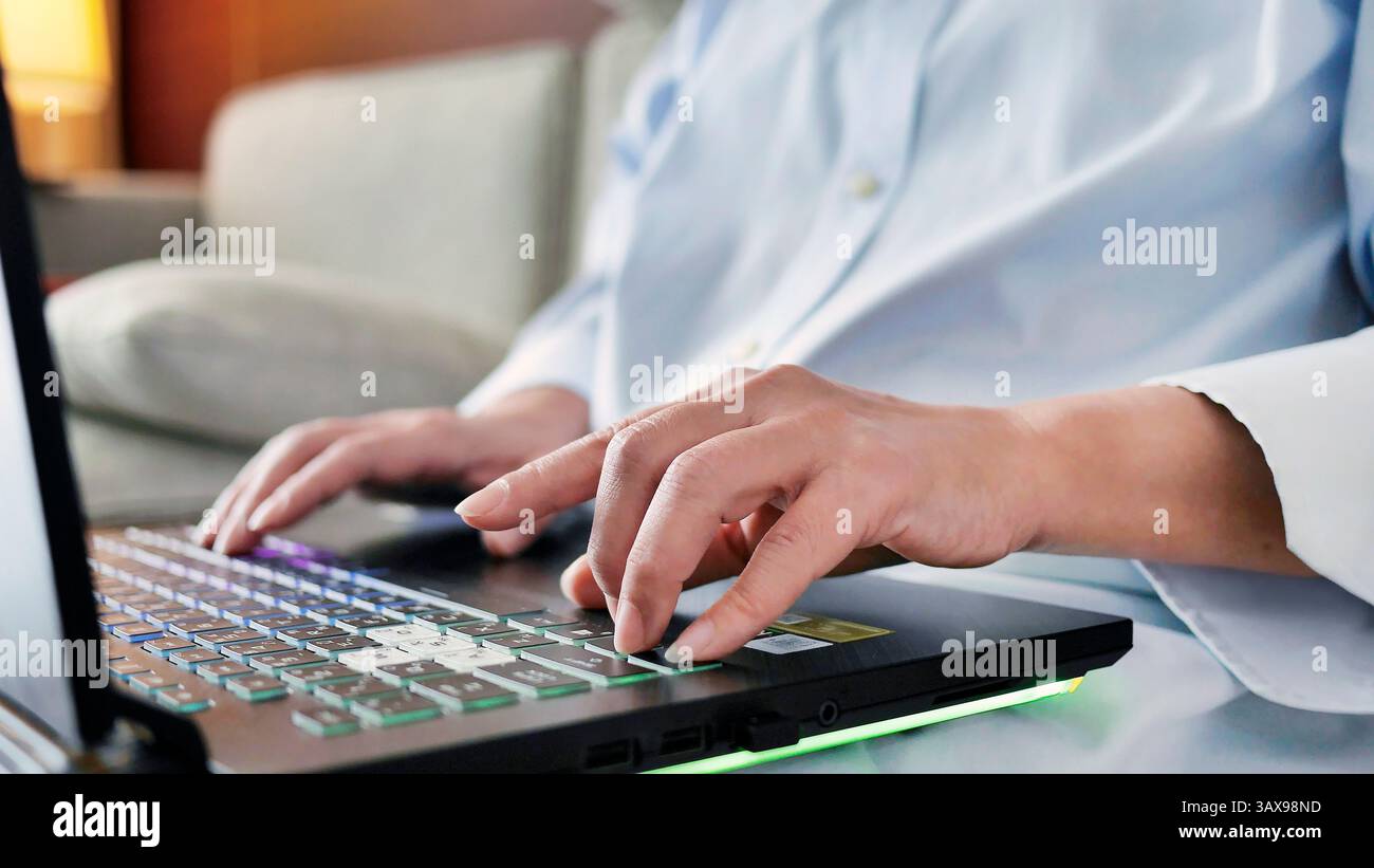 Close up Female hands using laptop computer, typing on keyboard while sitting on sofa, programmer, solopreneur, remote work, work from home, freelance Stock Photo