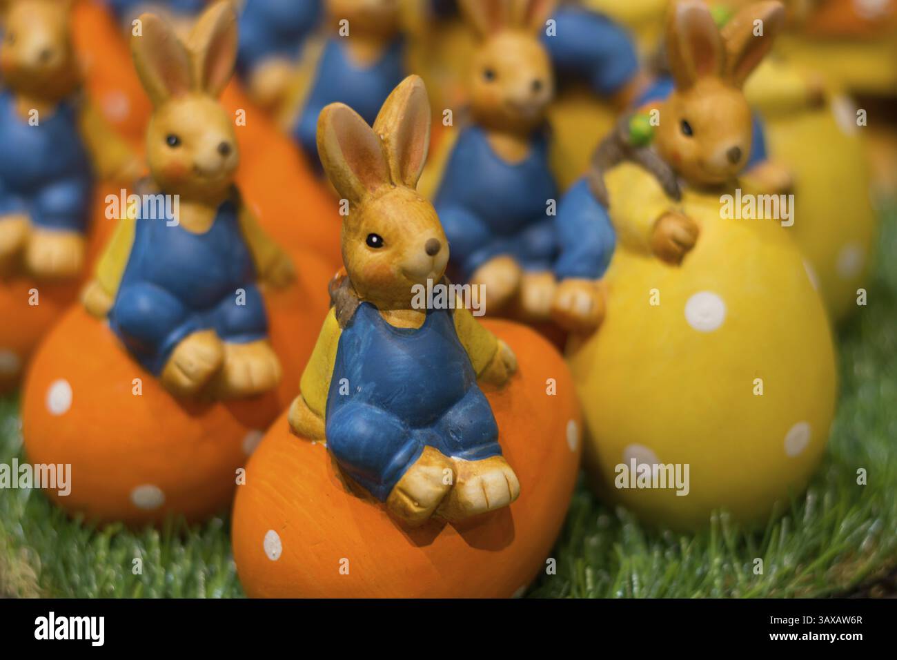 Numerous colourful ceramic Easter bunnies sit on colourful Easter eggs Stock Photo