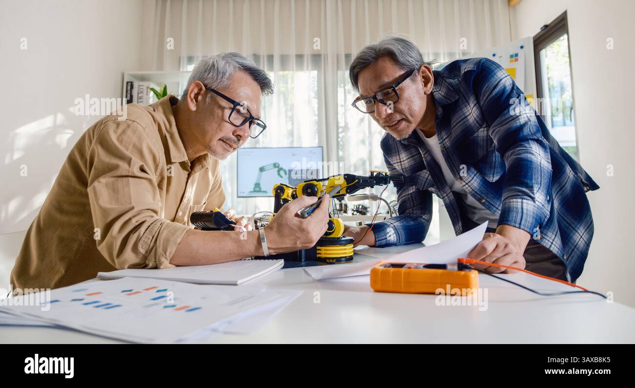 asian Senior engineer programming robot arm in automation and electronics technology lab Stock Photo