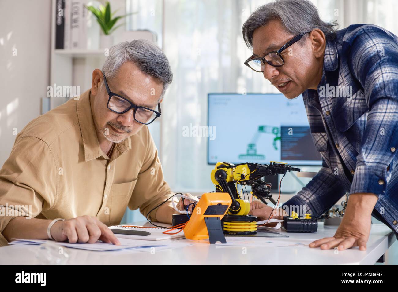 asian Senior engineer programming robot arm in automation and electronics technology lab Stock Photo