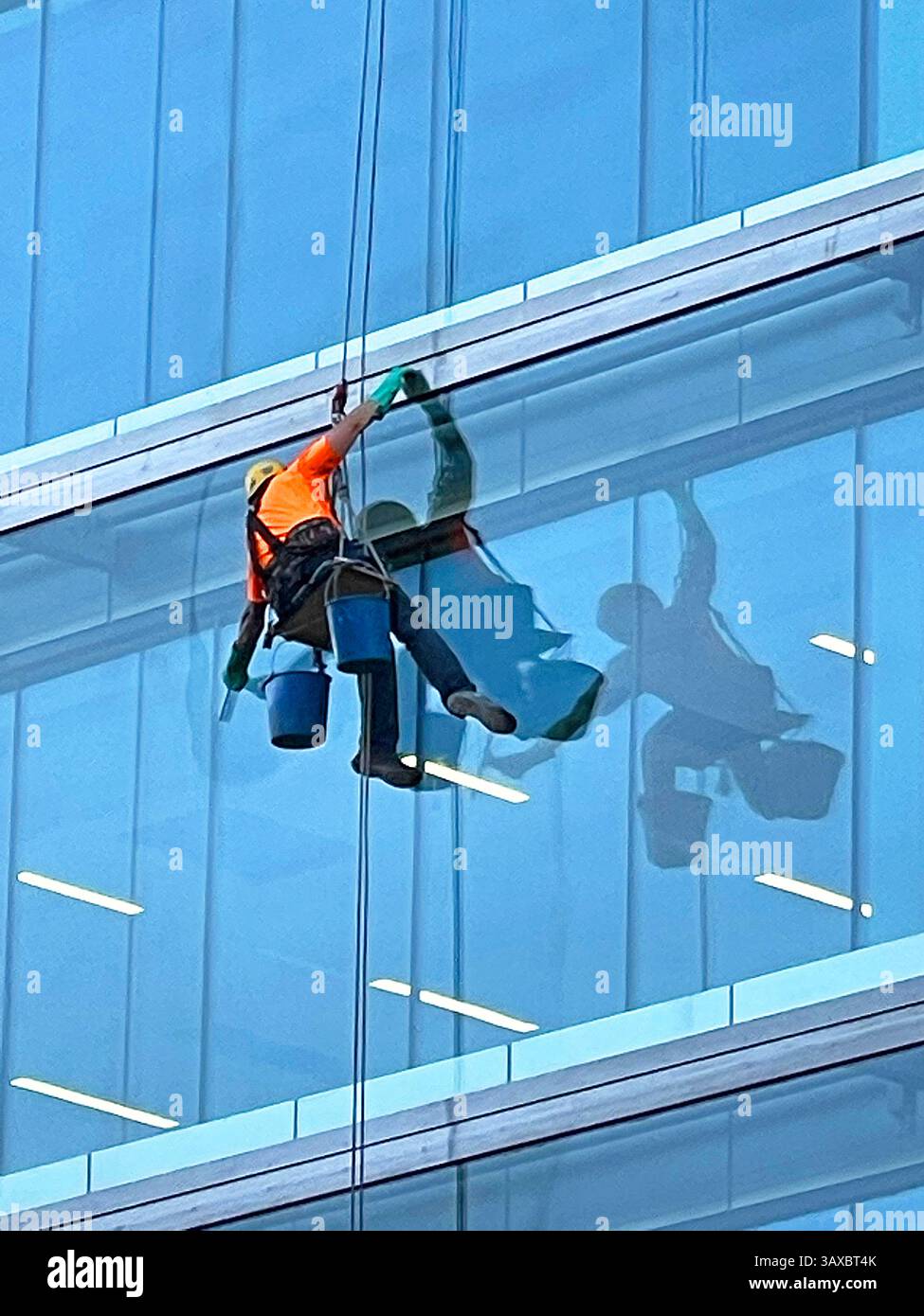 Window washer cleaning a glass facade. Madrid, Spain. - Smartphone Captured Stock Image