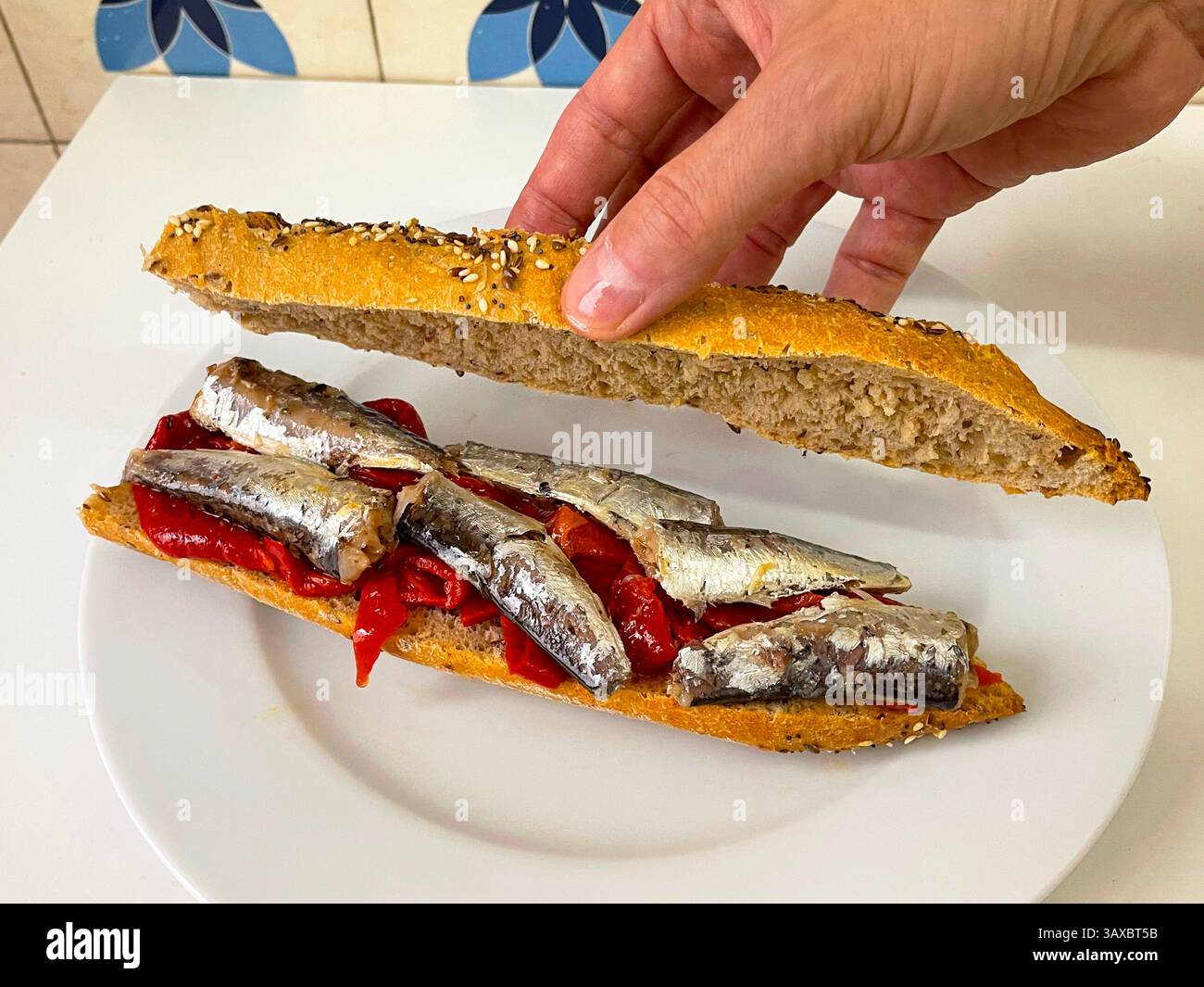 Hand preparing a red peppers and sardines on integral bread. - Smartphone Captured Stock Image