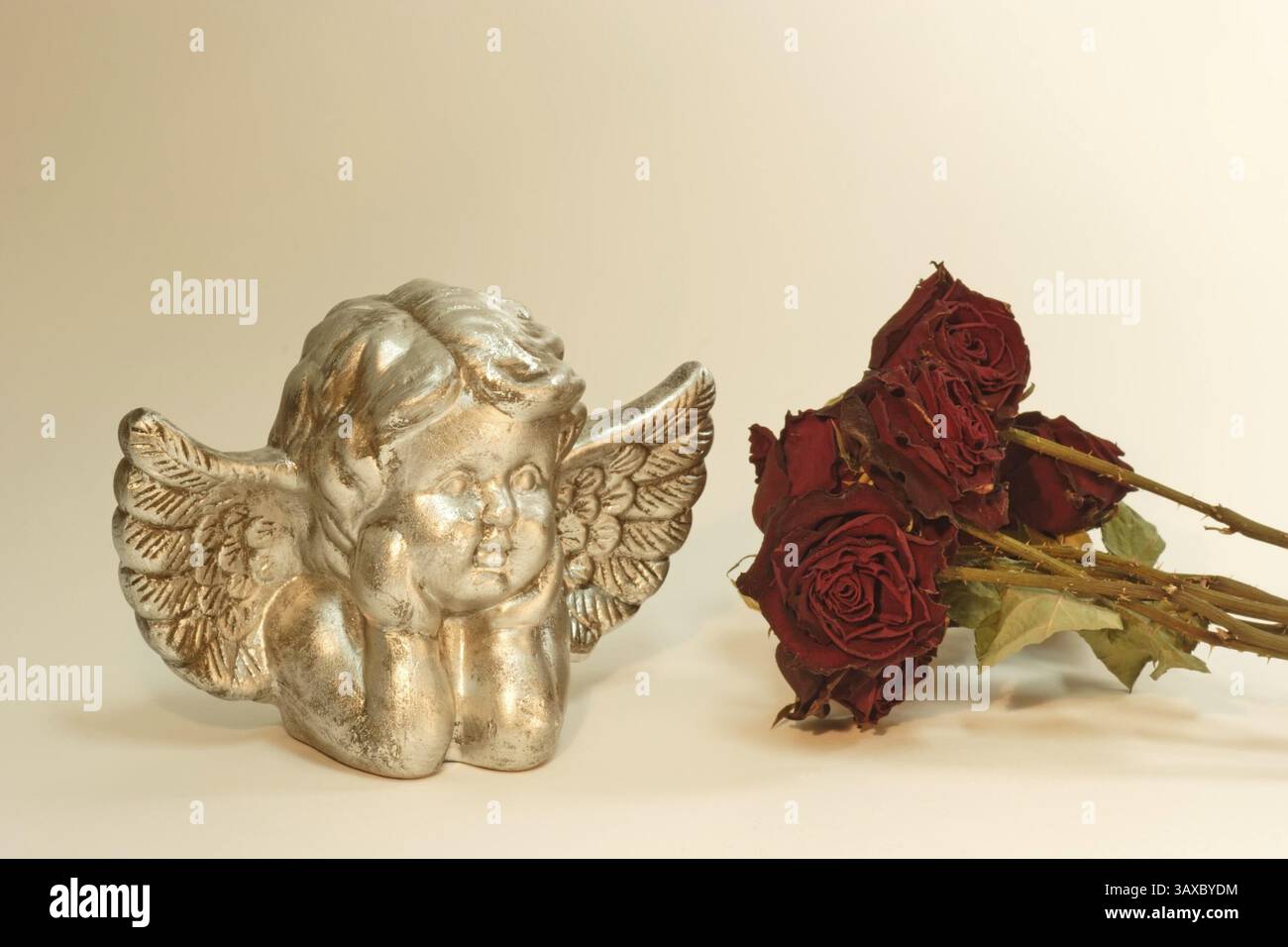 Golden angel with dried red roses Stock Photo - Alamy