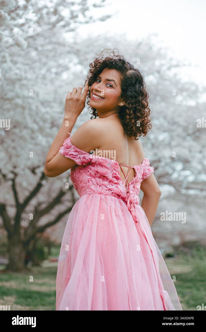 A woman in a long pink dress stands in a half-turned position Stock ...