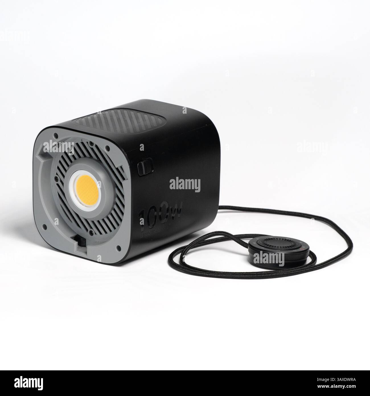 Black Aputure 100d LED light with foot stand and remote controller on white surface. Stock Photo