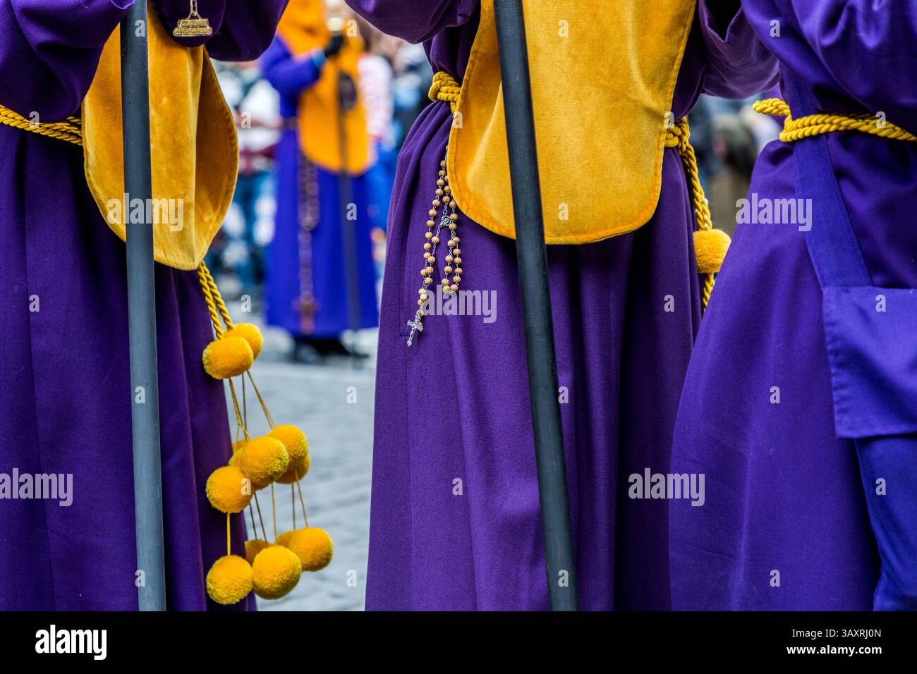 Good Friday procession En el Calvario in Cuenca. Processionists in purple robes with yellow details and rosaries. Plaza Mayor, Cuenca, Castile-La Mancha, Spain Stock Photo