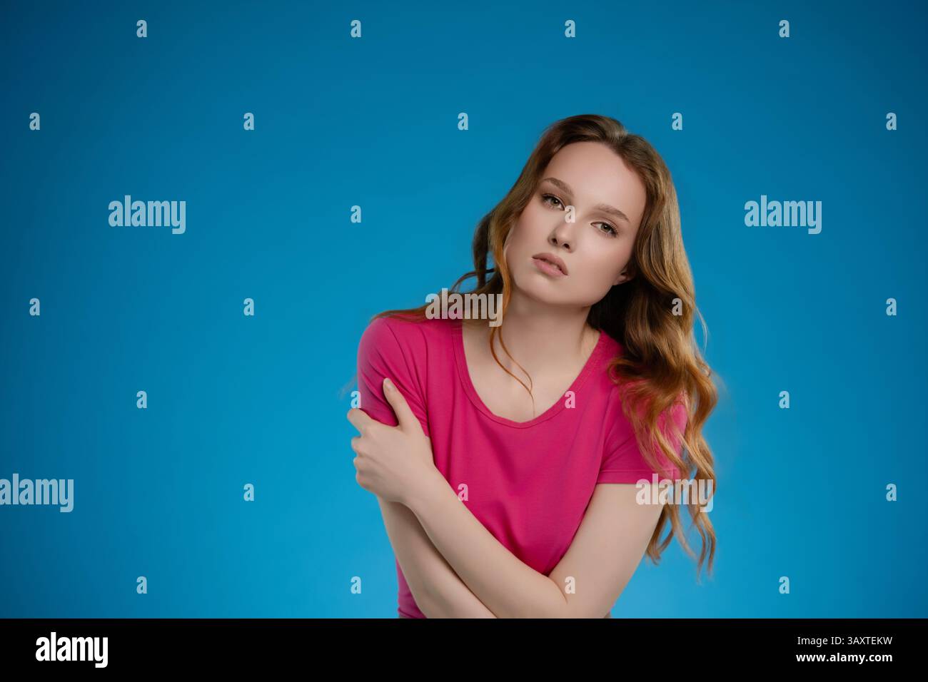 Confident woman poses in studio setting against vibrant blue background expressing a range of emotions Stock Photo