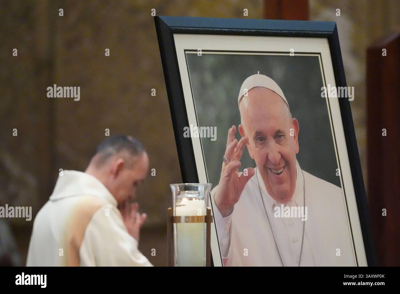 A priest prays during a service in honor of Pope Francis at the ...