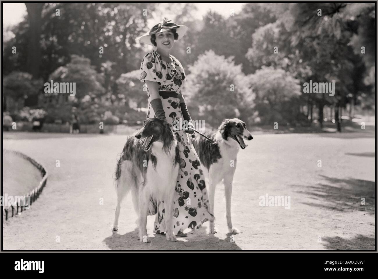 1930s Paris French Fashion Lifestyle lady woman female model Bois de Boulogne Fashion photography Description : Woman with two dogs two Borzoi dogs, also known as Russian Wolfhounds in the Bois de Boulogne Date : June 1936 Stock Photo