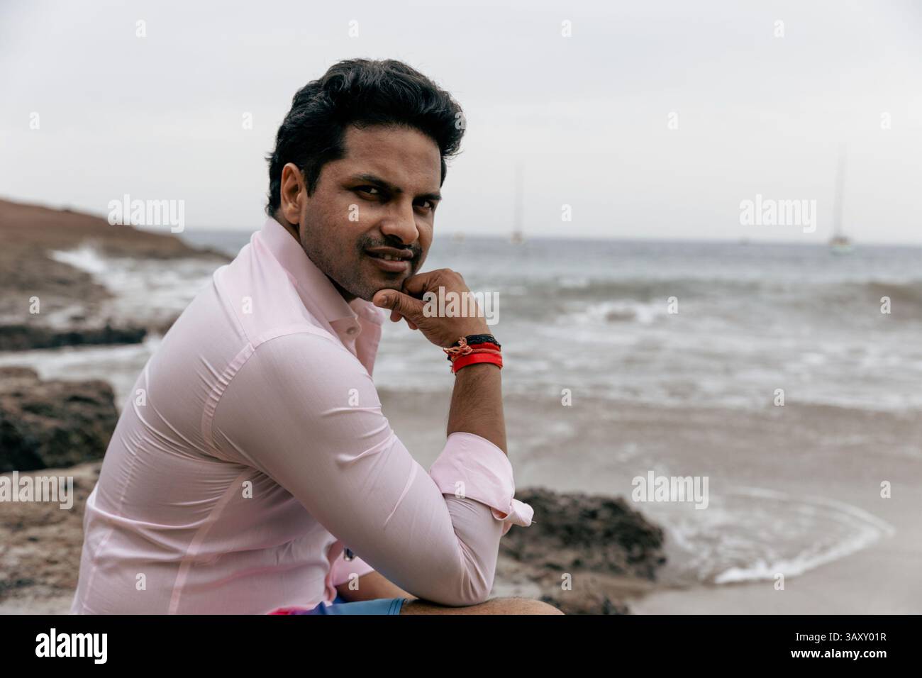 Pensive confident man at the beach wearing a shirt and looking at the camera. Stock Photo