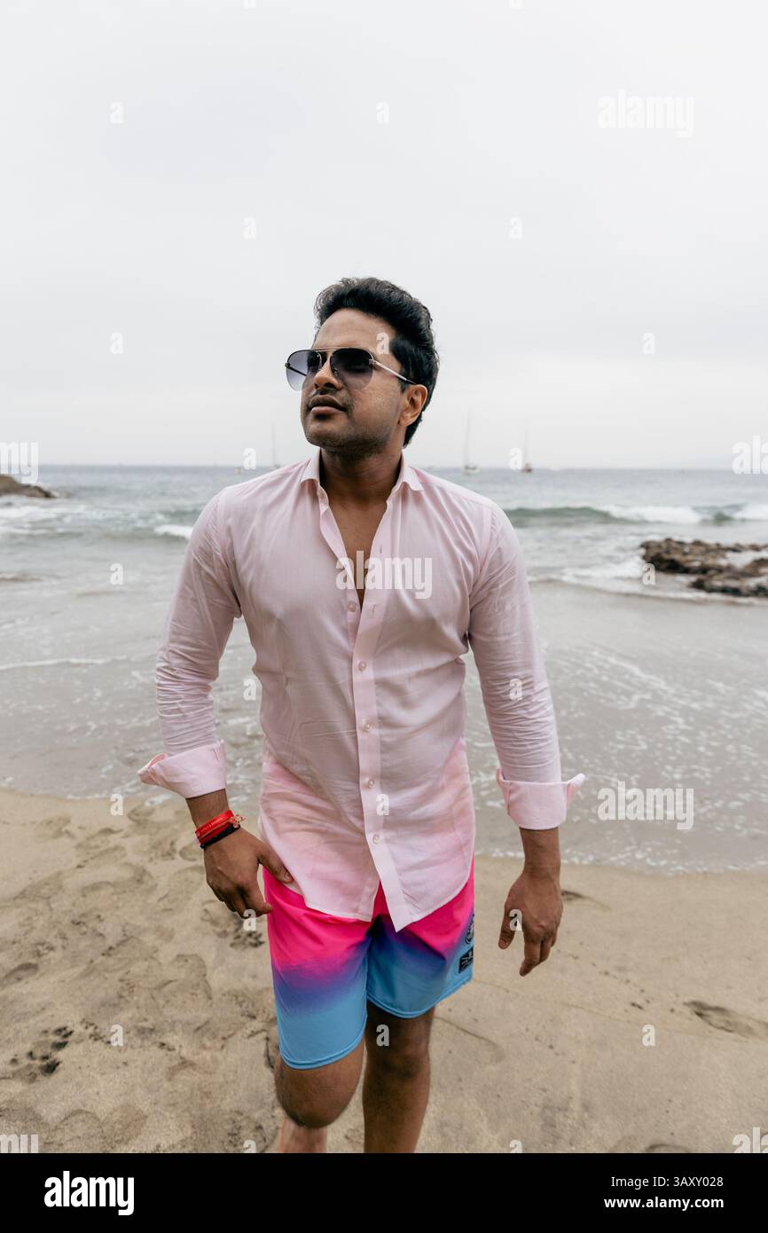 A wealthy Indian man at the beach relaxing and enjoying his vacation, wearing sunglasses. Stock Photo