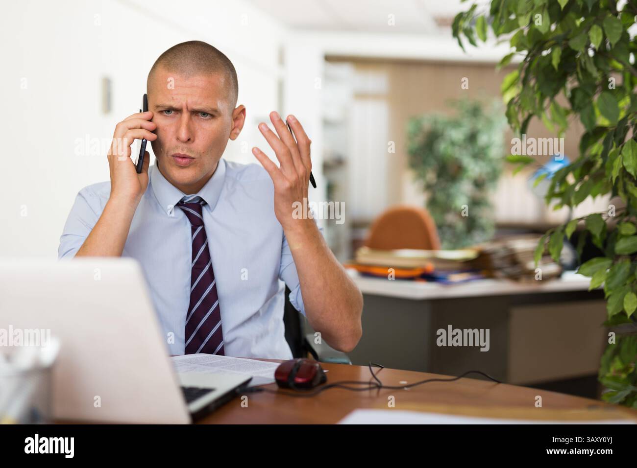 Irritated businessman having difficult phone talk Stock Photo