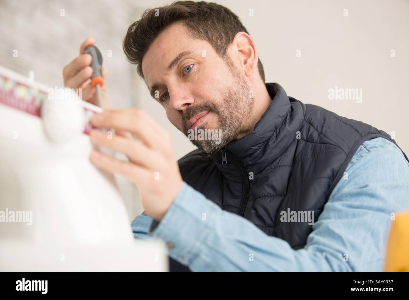 orker installing window curtain rod on the wall Stock Photo