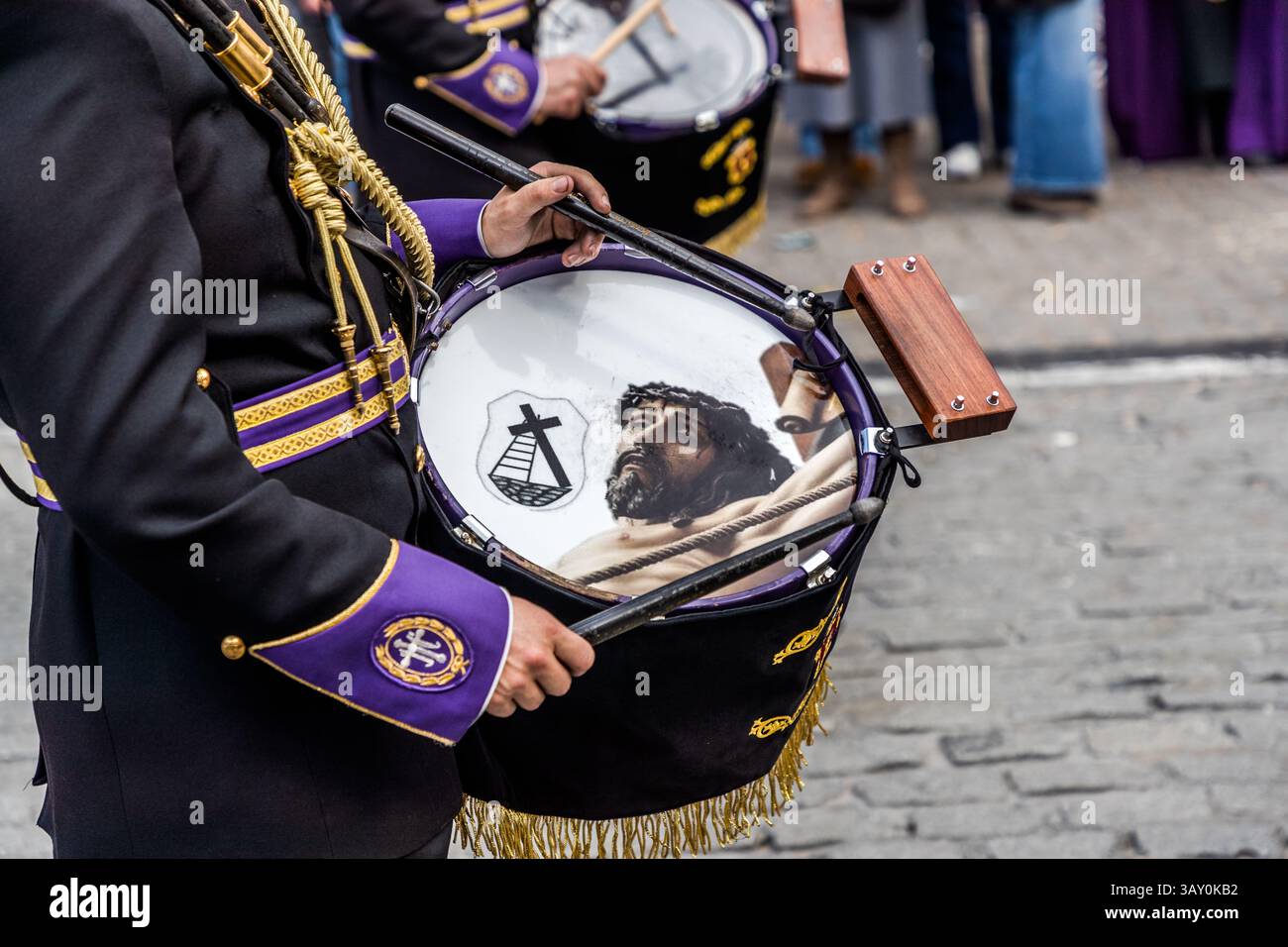 Good Friday procession En el Calvario in Cuenca. Plaza Mayor, Cuenca, Castile-La Mancha, Spain. A musician in traditional dress plays a drum with an image of Jesus Christ in the Plaza Mayor of Cuenca, Spain.  The drum is played during a religious procession. Stock Photo