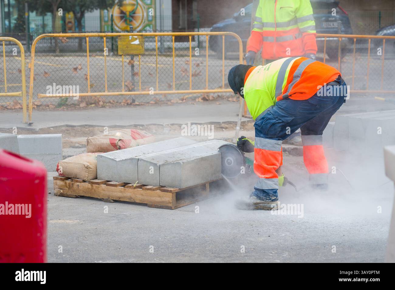 Road workers in yellow overalls repair sidewalk and highway to village Stock Photo
