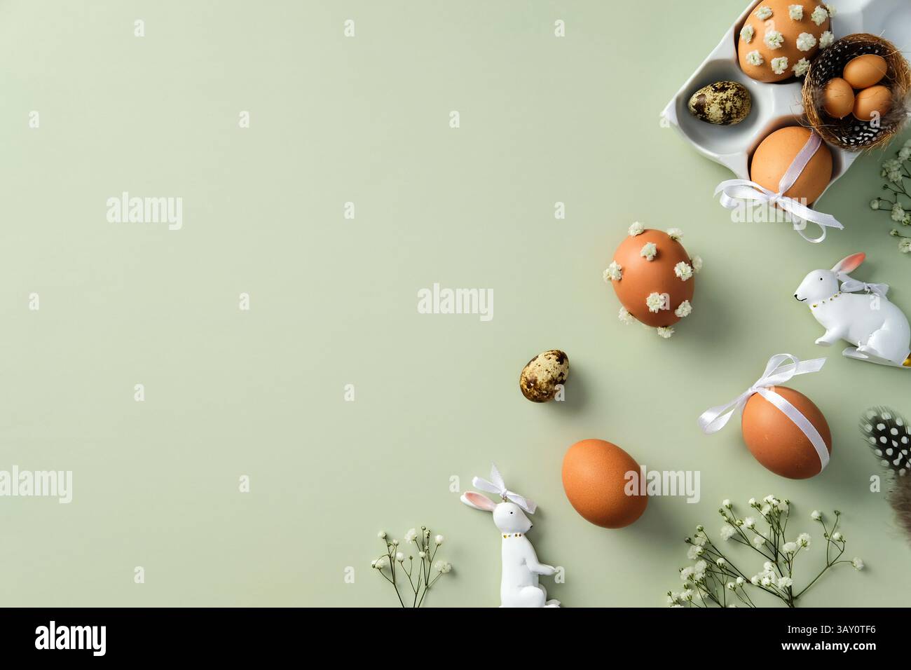 Flat lay composition with Easter eggs, ceramic bunnies, flower branches on pastel green background Stock Photo