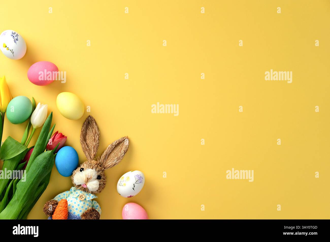 Happy Easter concept. Flat lay composition with colorful eggs, tulips and decorative Easter bunny Stock Photo