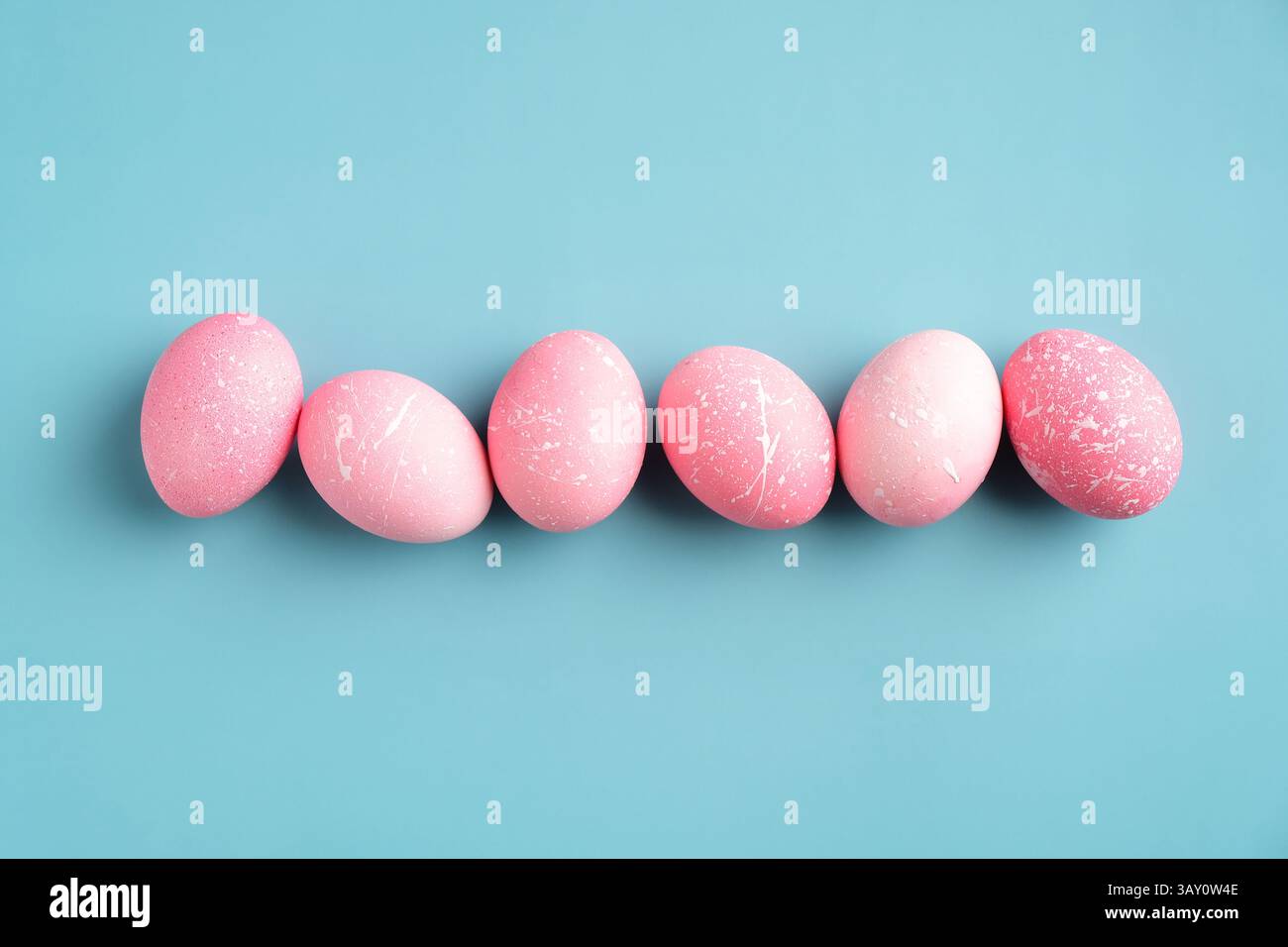 Row of pink Easter eggs on turquoise background. Happy Easter minimal concept. Flat lay, top view. Stock Photo