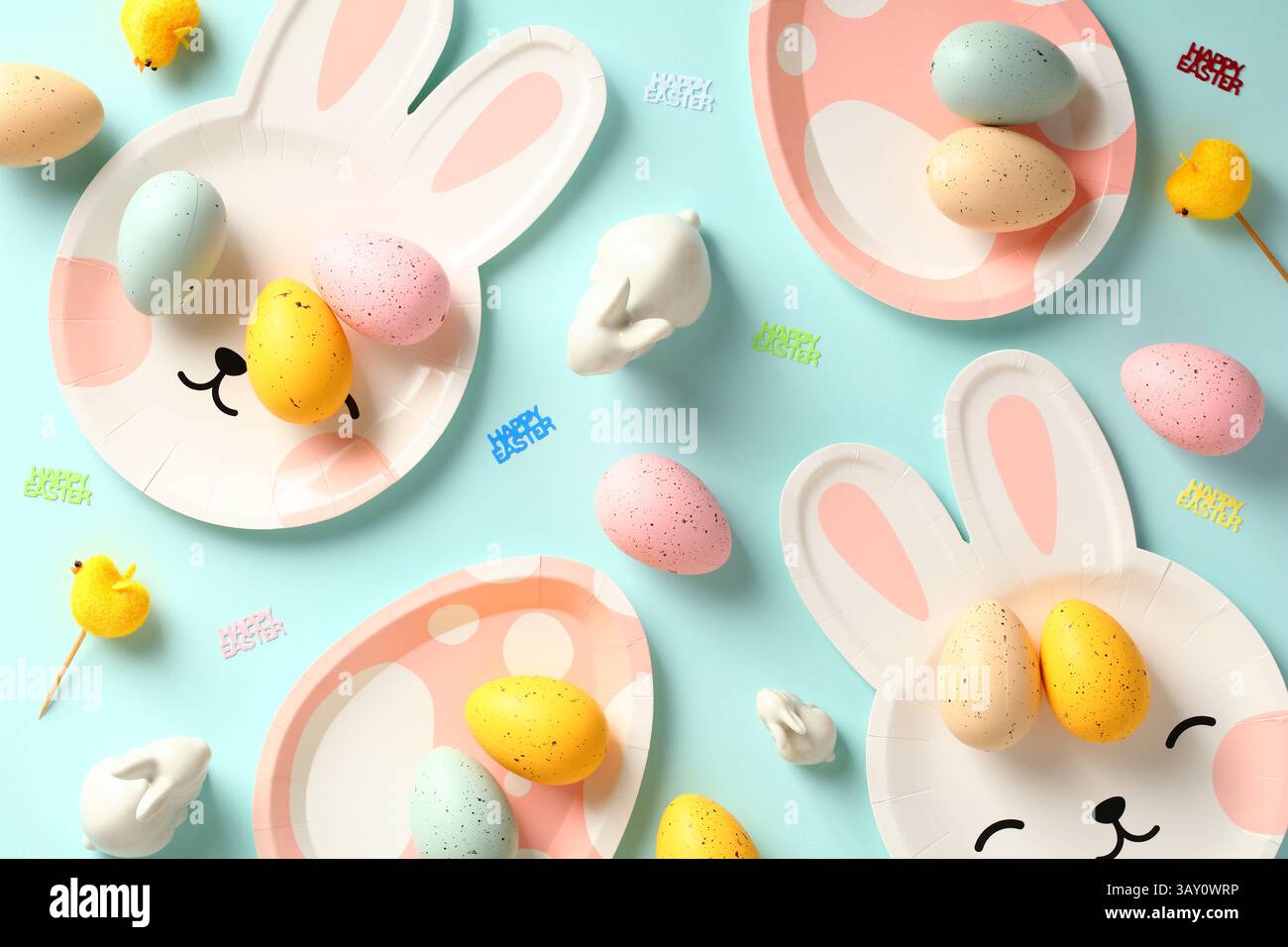 Happy Easter concept. Easter table with plates, colorful eggs and decorations on blue background. Stock Photo