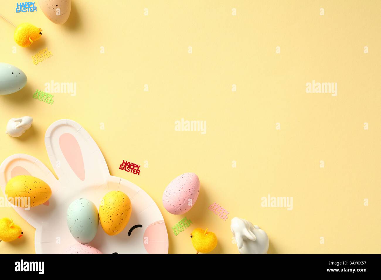 Happy Easter creative layout with Easter eggs, decorative chickens, rabbits on pastel yellow table. Stock Photo