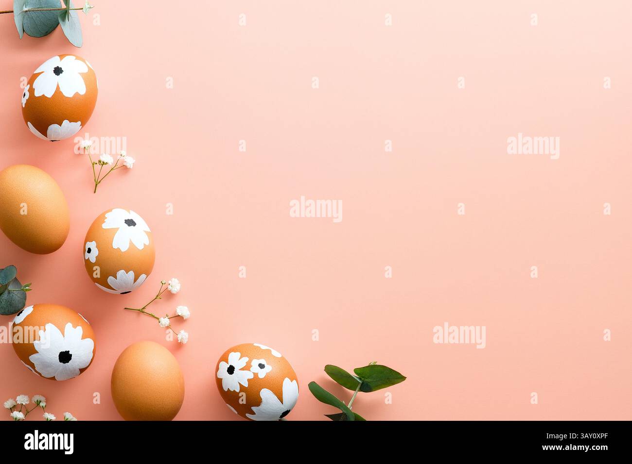Happy Easter card. Frame made of Easter eggs and spring flowers on pastel pink background. Flat lay, top view, copy space. Stock Photo