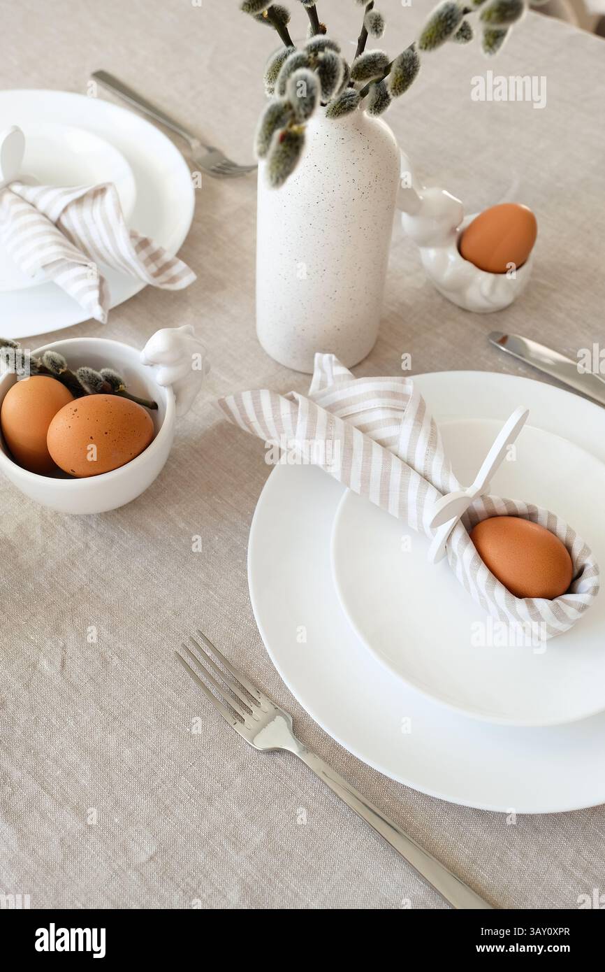 Easter still life. Easter dining table setting with Easter egg in bunny napkin and cutlery. Stock Photo