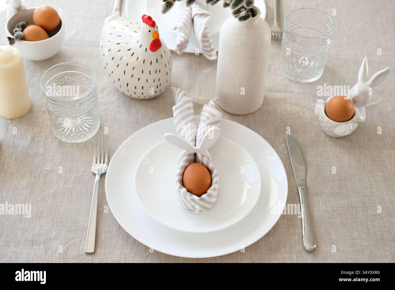 Easter table setting with egg in Easter bunny napkin on plate. Easter table serving. Stock Photo