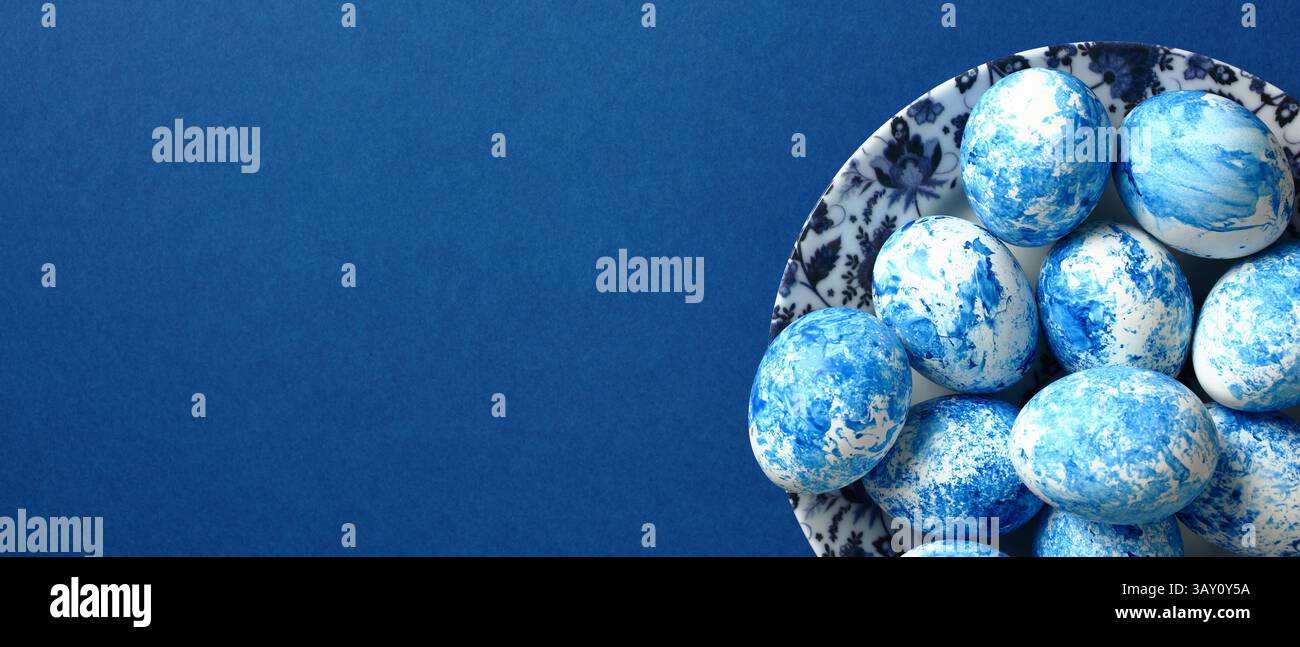 Painted blue Easter eggs on plate on dark blue background. Happy Easter banner template with copy space. Stock Photo