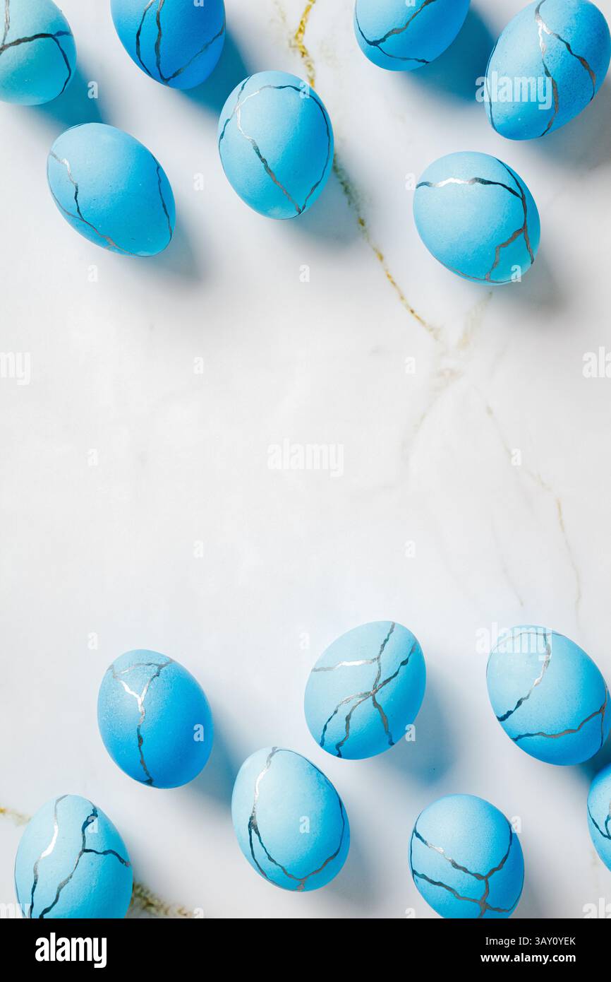 Vertical Easter background. Top view blue painted eggs on marble table. Stock Photo