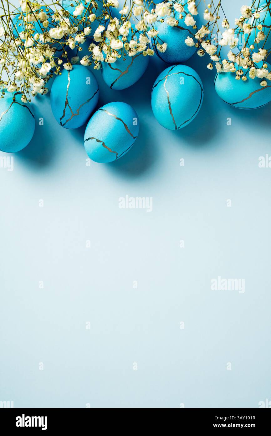 Elegant Easter eggs with spring flowers on pastel blue background ...