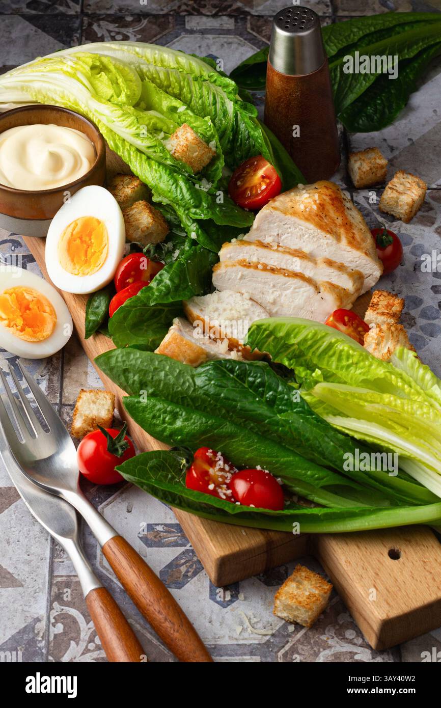 A vibrant image showing fresh Caesar salad ingredients, including romaine lettuce, grilled chicken, boiled eggs, croutons, and cherry tomatoes, neatly Stock Photo