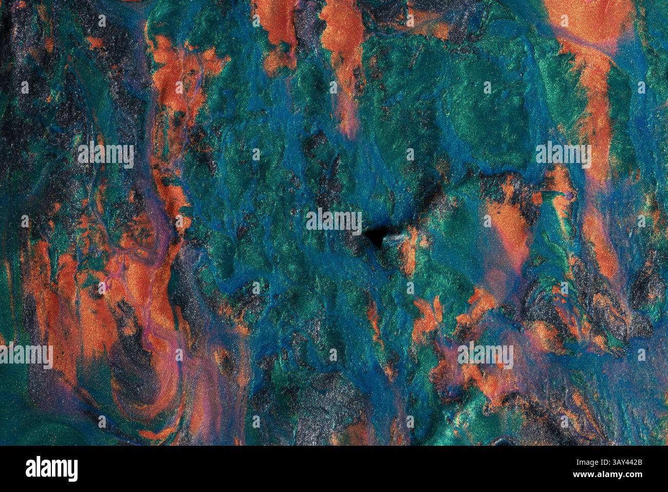 Vivid display of swirling metallic paints blending orange, blue, and green hues, creating a textured abstract background perfect for art and design. Stock Photo
