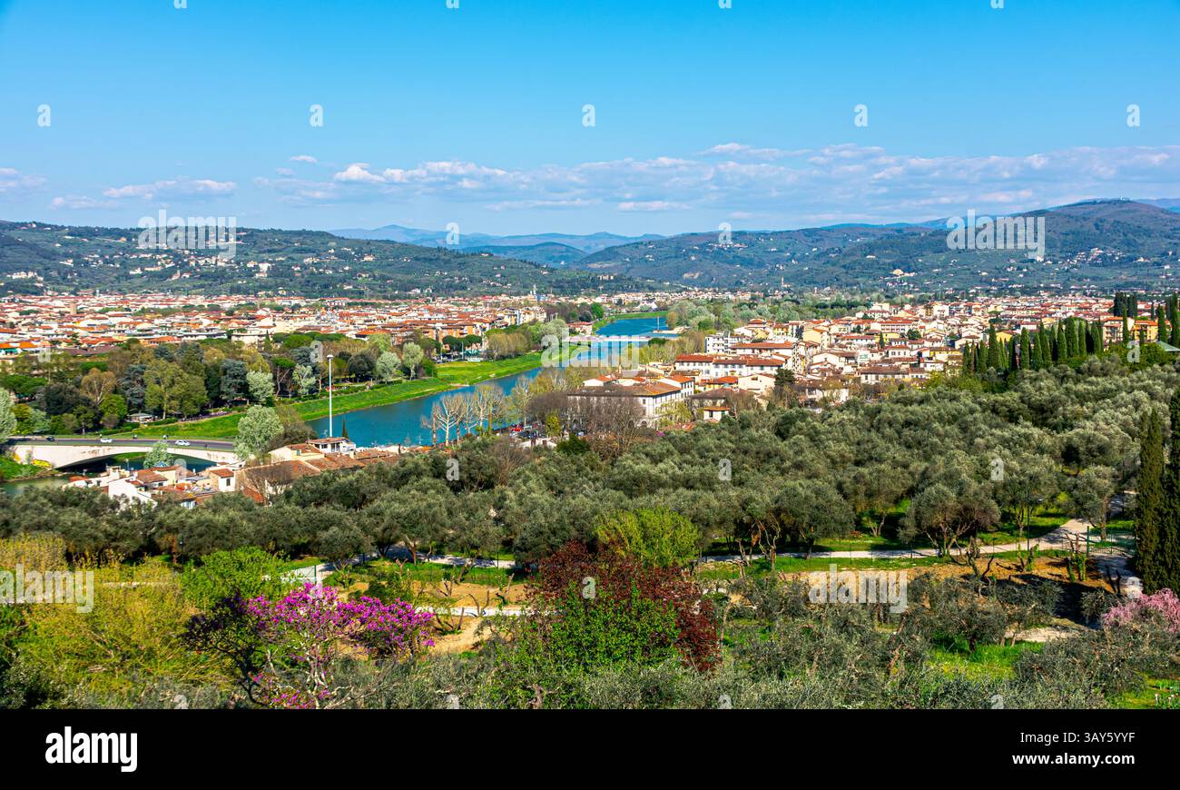 Scenic view of the Arno River winding through the hills and rooftops of Florence, surrounded by olive trees and Tuscan landscapes. Stock Photo