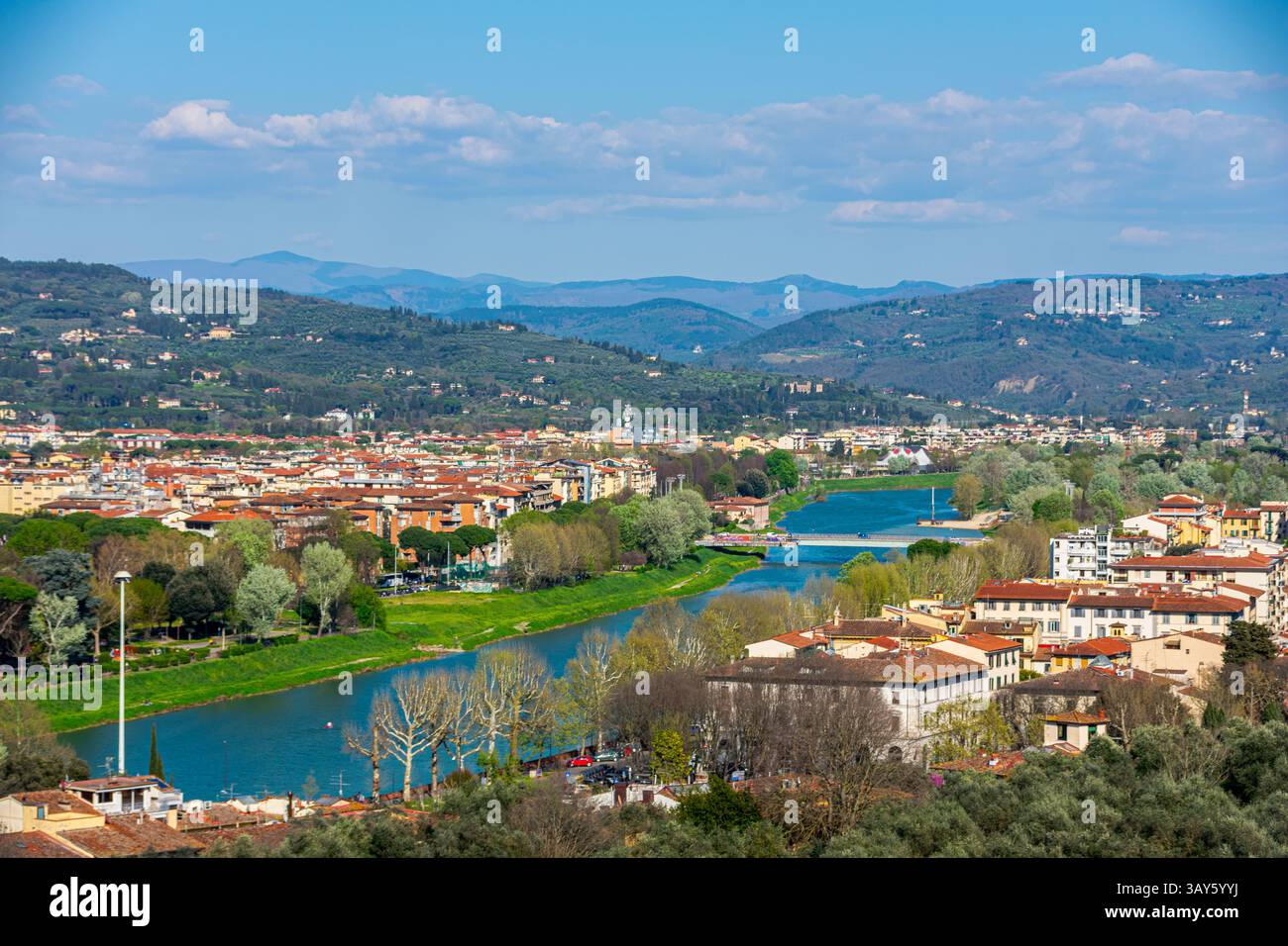 Scenic view of the Arno River winding through the hills and rooftops of Florence, surrounded by olive trees and Tuscan landscapes. Stock Photo