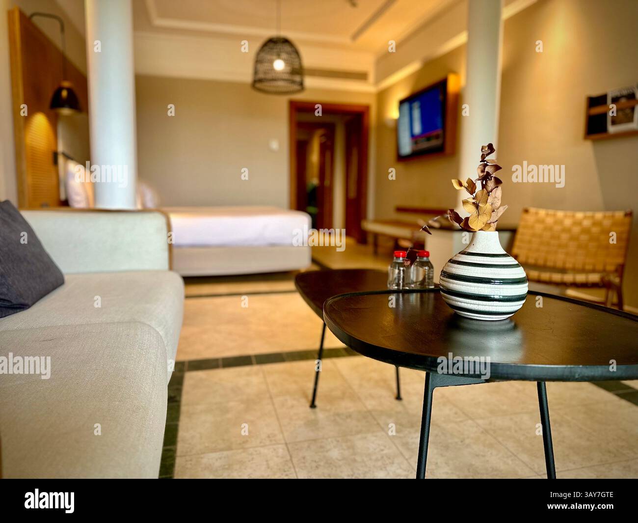 This image showcases a modern hotel room that exudes comfort and style. The cozy space is designed with minimalist elegance, featuring a soft beige so - Smartphone Captured Stock Image