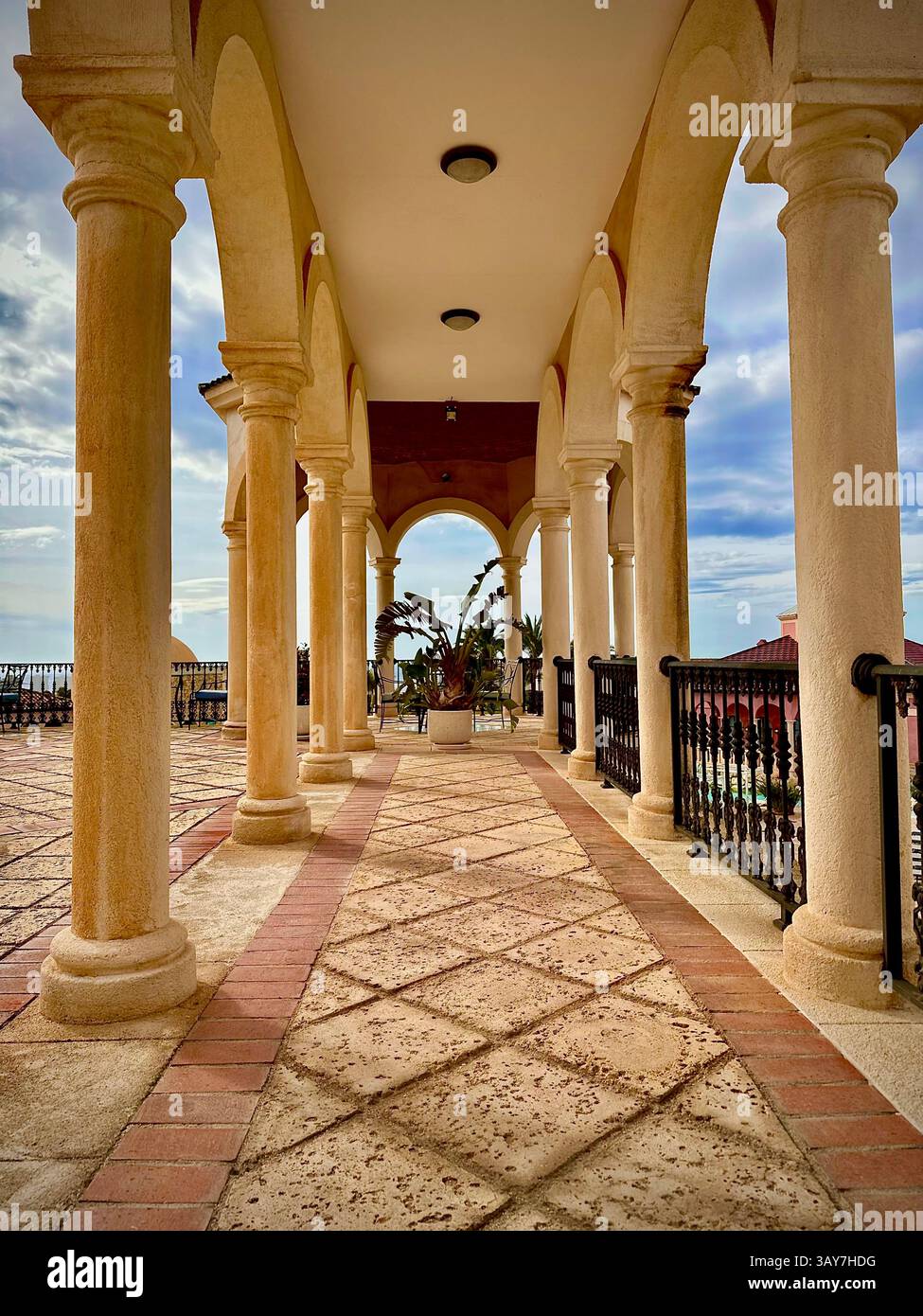 This photo showcases a symmetrical stone archway framed by classical columns leading into a serene garden pathway. The composition highlights the symm - Smartphone Captured Stock Image